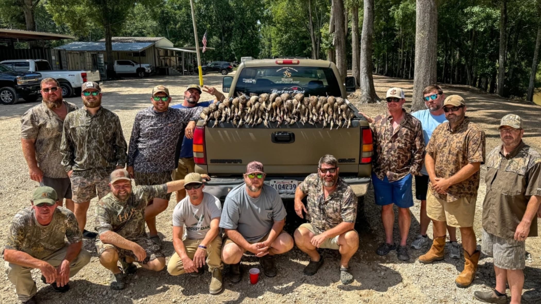 Group of men with harvested birds in the back of a truck. Hunters pose in front of their catch, smiling at the camera.
