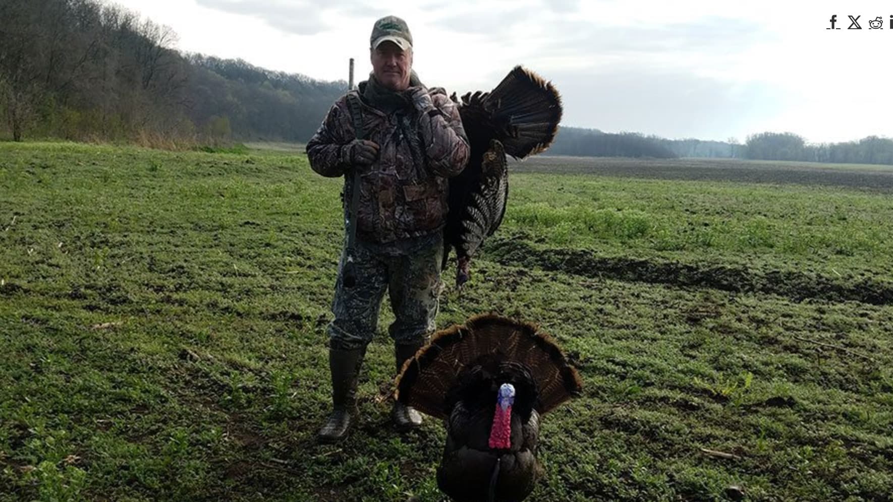 Hunter in camouflage holds a large turkey over his shoulder, with another turkey in the foreground.