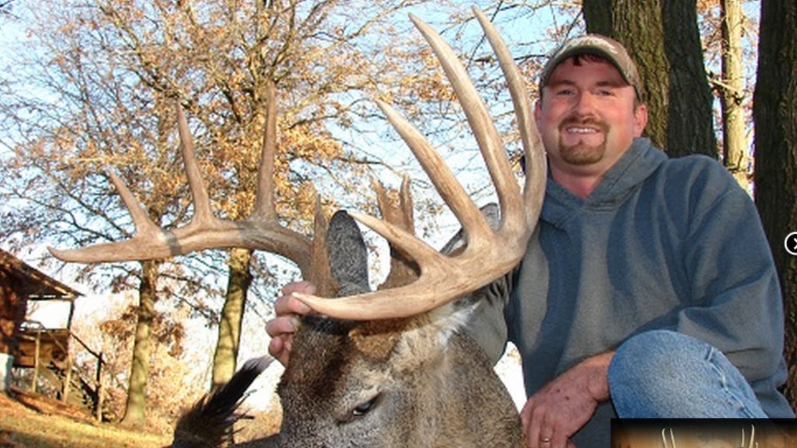 Man with a large deer rack and impressive antlers outdoors.