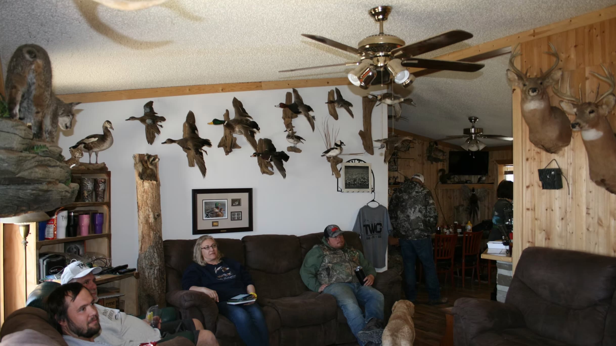 People relax in a room decorated with taxidermied animals, including deer heads and ducks.